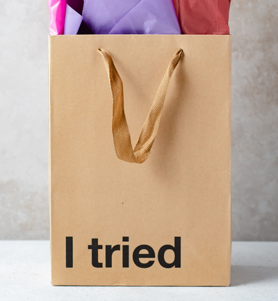 Funny kraft gift bags on a table with the saying "I tried" on the gift bag